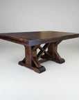 A rectangular, dark wood pedestal table with a visible grain pattern and a rounded tabletop edge. The table is supported by a central pedestal base with cross supports.