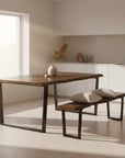 Wooden dining table with black metal legs and matching bench on a white background