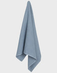 A light blue ribbed cotton towel hanging vertically against a plain white background.