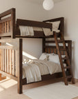 Wooden loft bed with ladder on a wooden floor against a white wall
