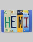 A custom license plate sign made from repurposed license plates, mounted on a wooden background with a variety of colorful text and graphics.