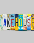 A custom license plate sign made from repurposed license plates, mounted on a wooden board with a colorful array of plates featuring various text and graphics, and the word 'LAKEHOUSE' prominently displayed.