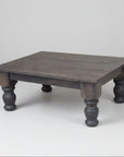 A rectangular rustic coffee table with turned legs, made of Canadian solid wood, with a handplaned top finish in a dark color.
