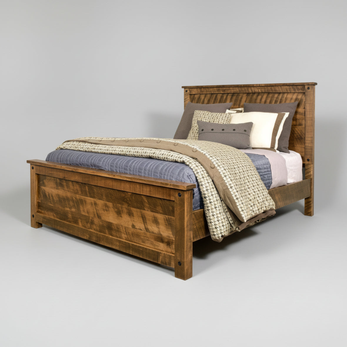 A rustic Adirondack style bed made of solid wood, with a high headboard and footboard, displayed with bedding and pillows.