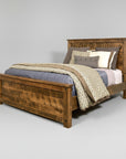 A rustic Adirondack style bed made of solid wood, with a high headboard and footboard, displayed with bedding and pillows.
