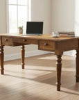 A wooden desk with three drawers and turned legs, finished in a standard wood texture.