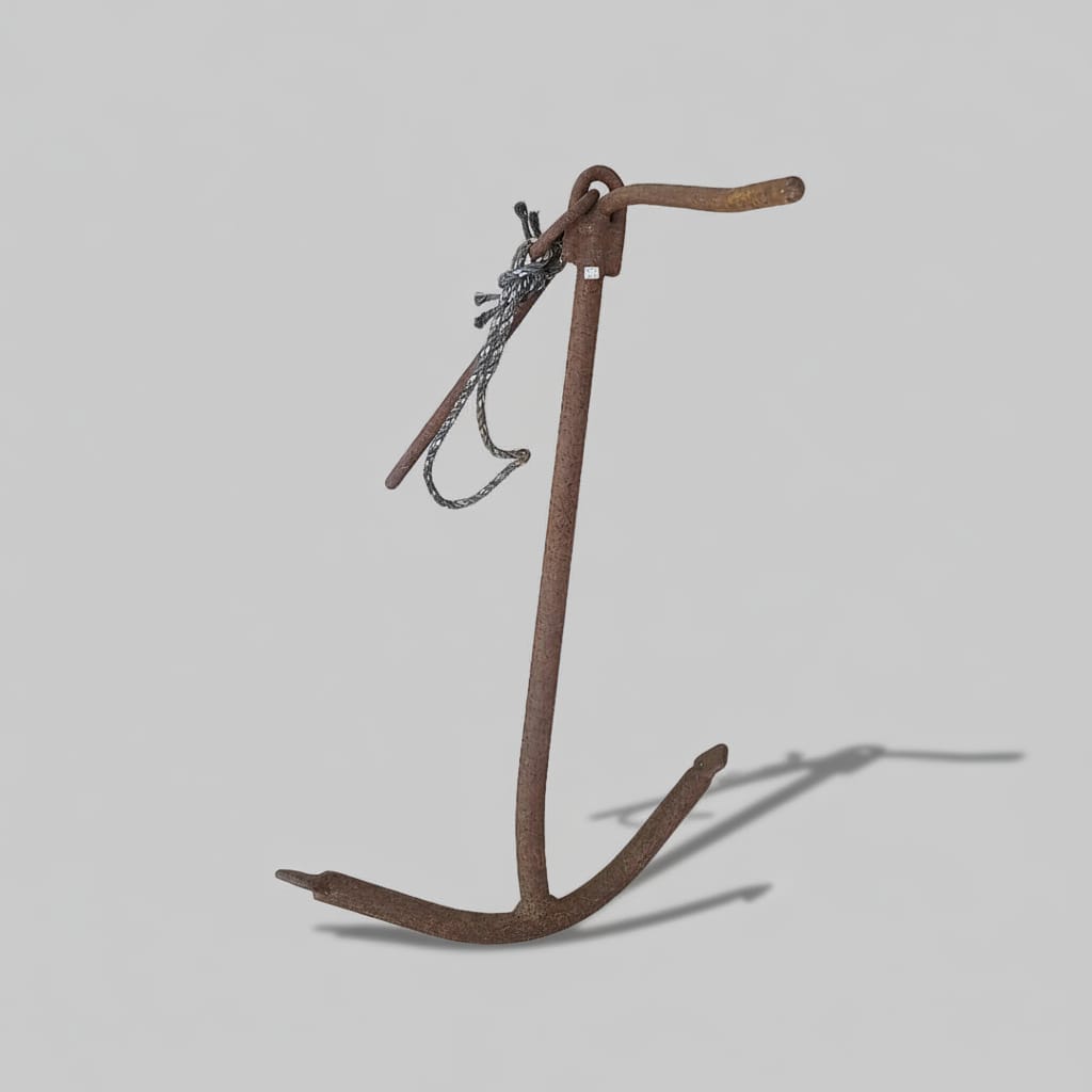 A rusted metal anchor with a chain, photographed on a concrete floor.