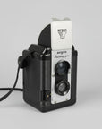 A vintage black and silver Shibe S-16 slide camera resting on a weathered, peeling white-painted wooden surface.
