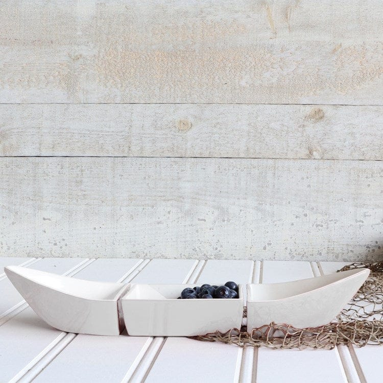 White ceramic canoe bowl with blueberries on a wooden surface.