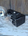 A vintage black wall-mounted camera with a silver dome reflector, photographed resting on weathered wooden boards.