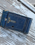 A vintage blue Kodak camera body resting on a weathered, white-painted wooden surface.