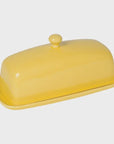 A yellow ceramic butter dish with a matching lid and small knob, shown on a light gray background.