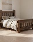 A rustic dark brown wooden bed frame with a slatted headboard and footboard, shown with patterned bedding and pillows on a white background.