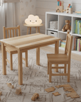 Children's wooden table and chairs in a room with toys and books.