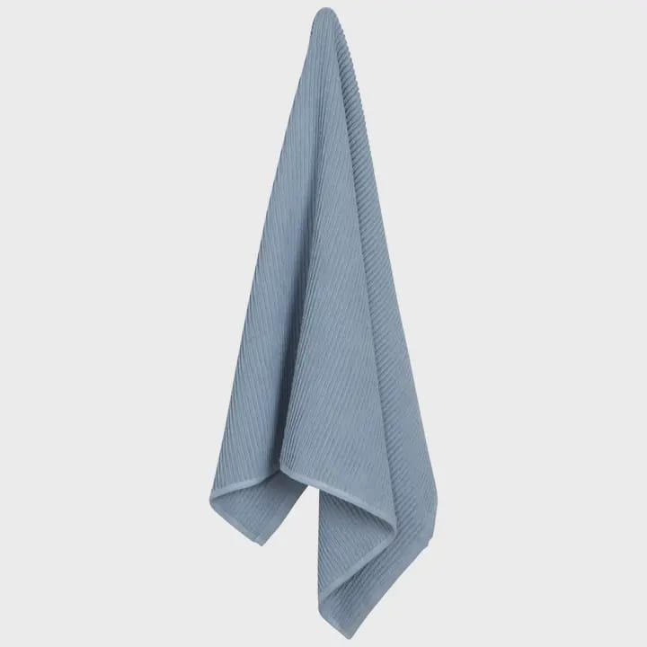 A light blue ribbed cotton towel hanging vertically against a plain white background.