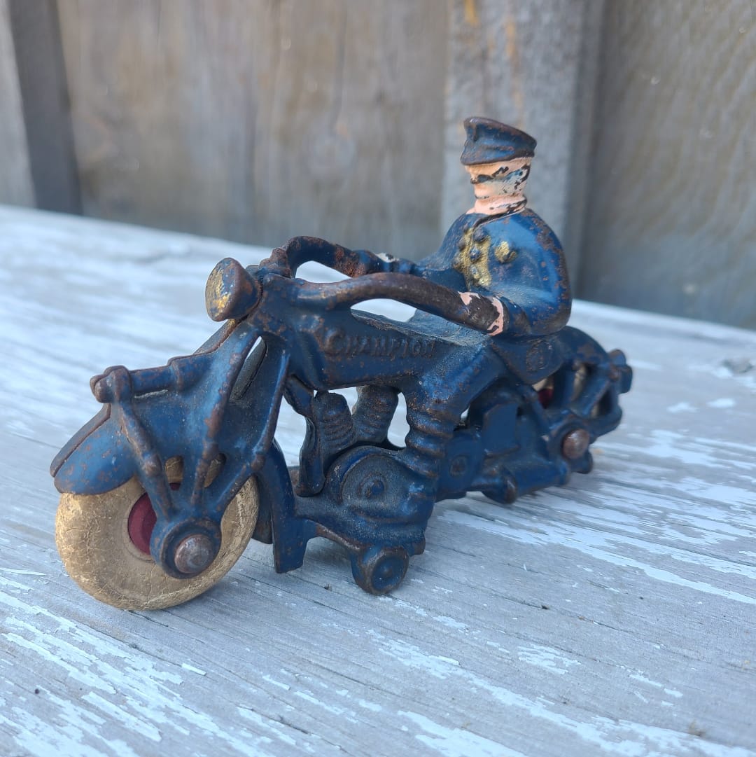 Vintage toy figure of a police officer on a motorcycle on a wooden surface