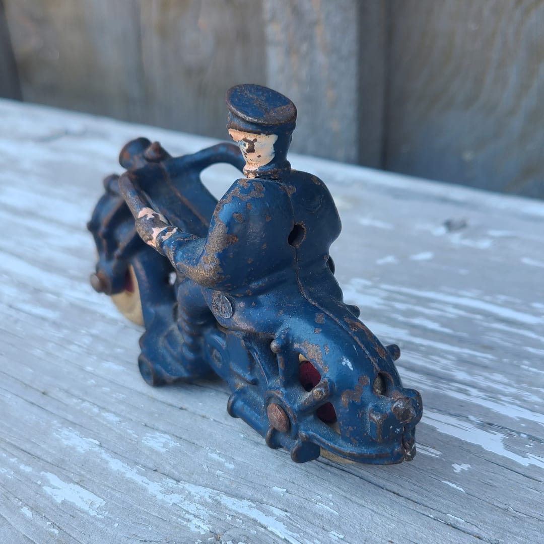Vintage blue cast iron toy figure of a person on a motorcycle