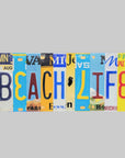 A rectangular decorative wall sign spelling 'BEACH LIFE' using colorful vintage license plate letters on a white background.