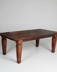 A rectangular, brown, solid wood dining table with visible wood grain and grooved leg design.