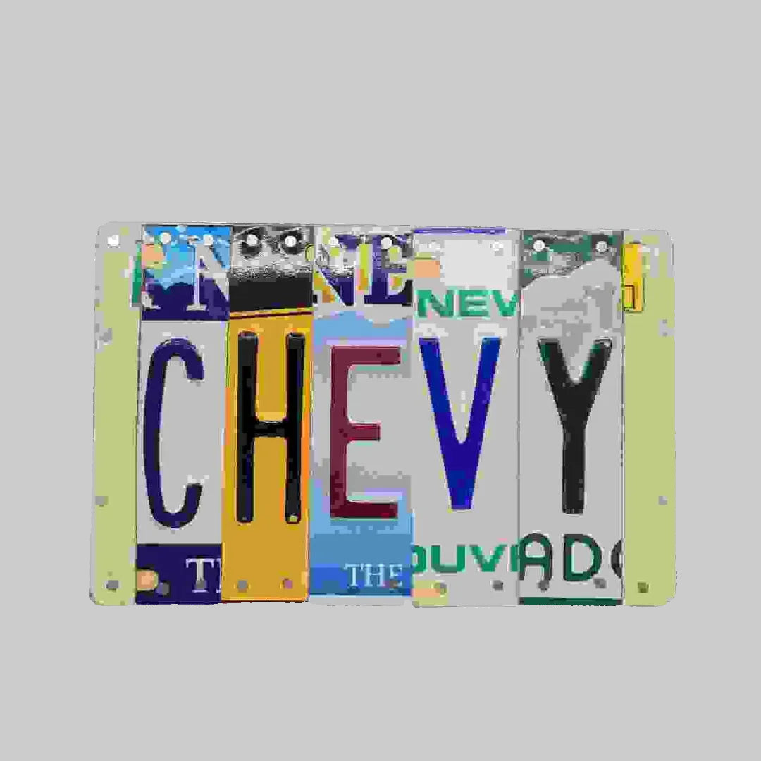 A custom license plate sign made from repurposed license plates, mounted on painted wood with various colors and text, including 'CHEVY' and 'THE OTHER GUY'.