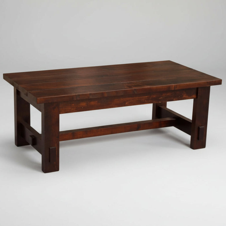 A rectangular, solid wood coffee table with a chunky plank top and visible saw marks, finished in a dark stain, with a sturdy frame.