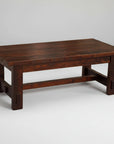 A rectangular, solid wood coffee table with a chunky plank top and visible saw marks, finished in a dark stain, with a sturdy frame.