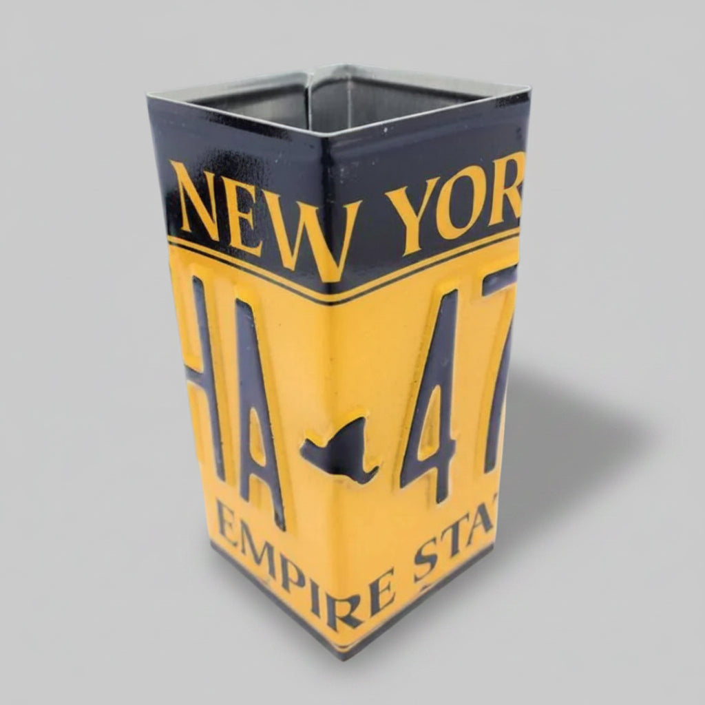 A pencil holder designed to resemble a New York license plate with a 'H47' sign-in style format, predominantly yellow with black text, placed on a white background.