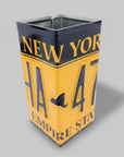 A pencil holder designed to resemble a New York license plate with a 'H47' sign-in style format, predominantly yellow with black text, placed on a white background.