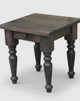 A rustic wooden end table with handcrafted turned legs and a drawer, made from solid wood.