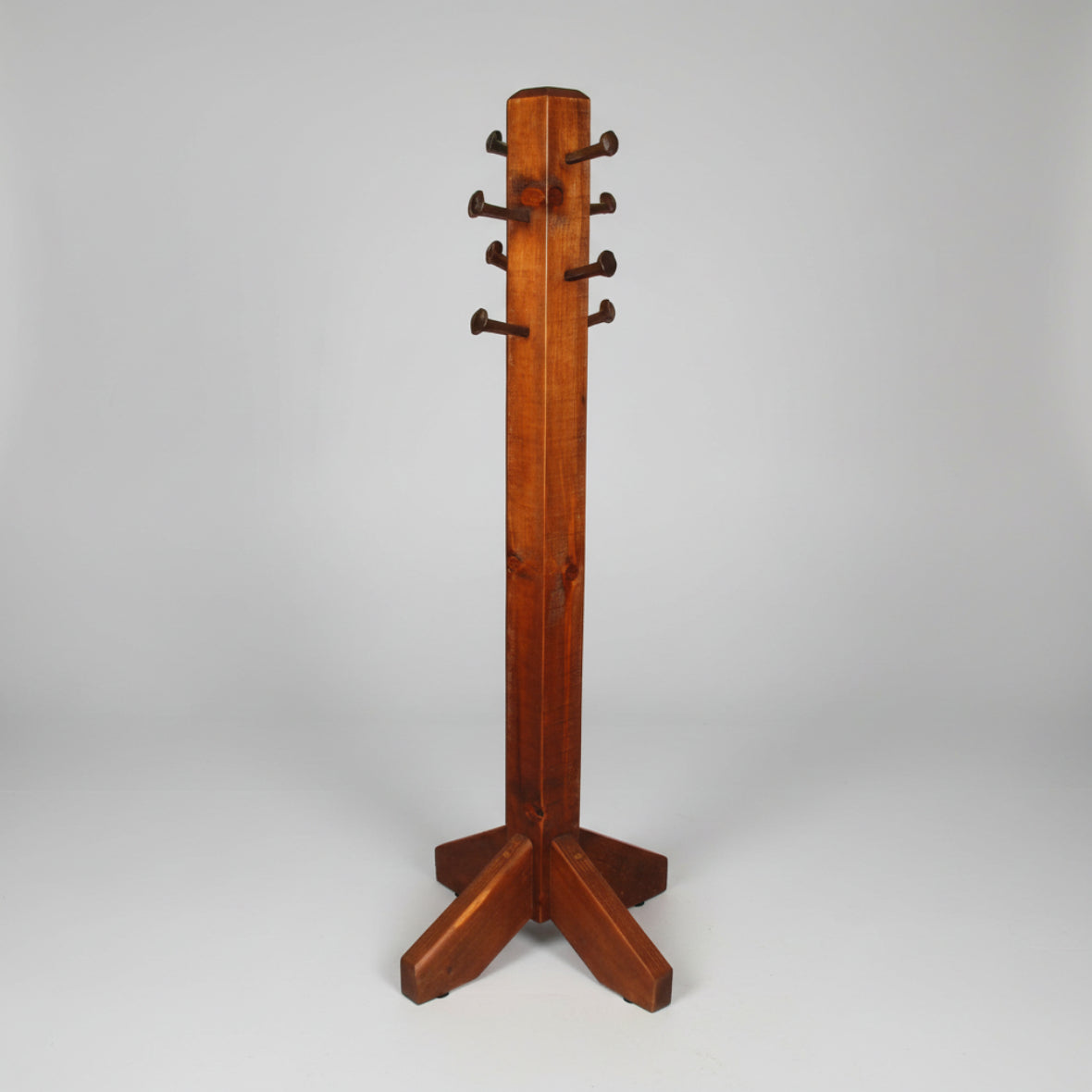 A brown wooden hall tree with a rustic design, featuring multiple hooks for hanging items, crafted using techniques that include nail and spike insertion.