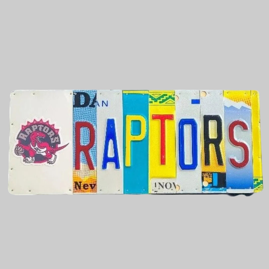A custom license plate sign featuring the word 'RAPTORS' in vibrant colors on a wooden background with a logo and text.