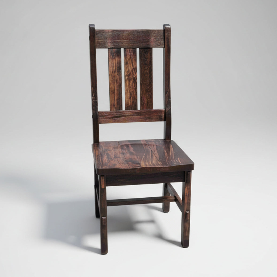 A wooden chair with a slat back and a scooped seat, featuring bolt accents and armrests.
